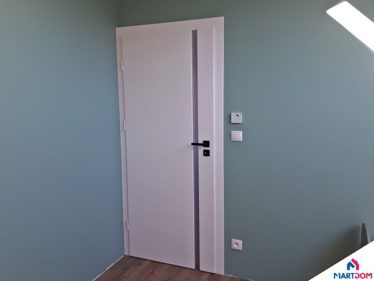 Drzwi pokojowe białe Erkado Baldur z szybą pionową mat kolor pokoju jasny niebieski czarna klamka ciemne panele widok od pokoju osłonki białe na zawiasy
