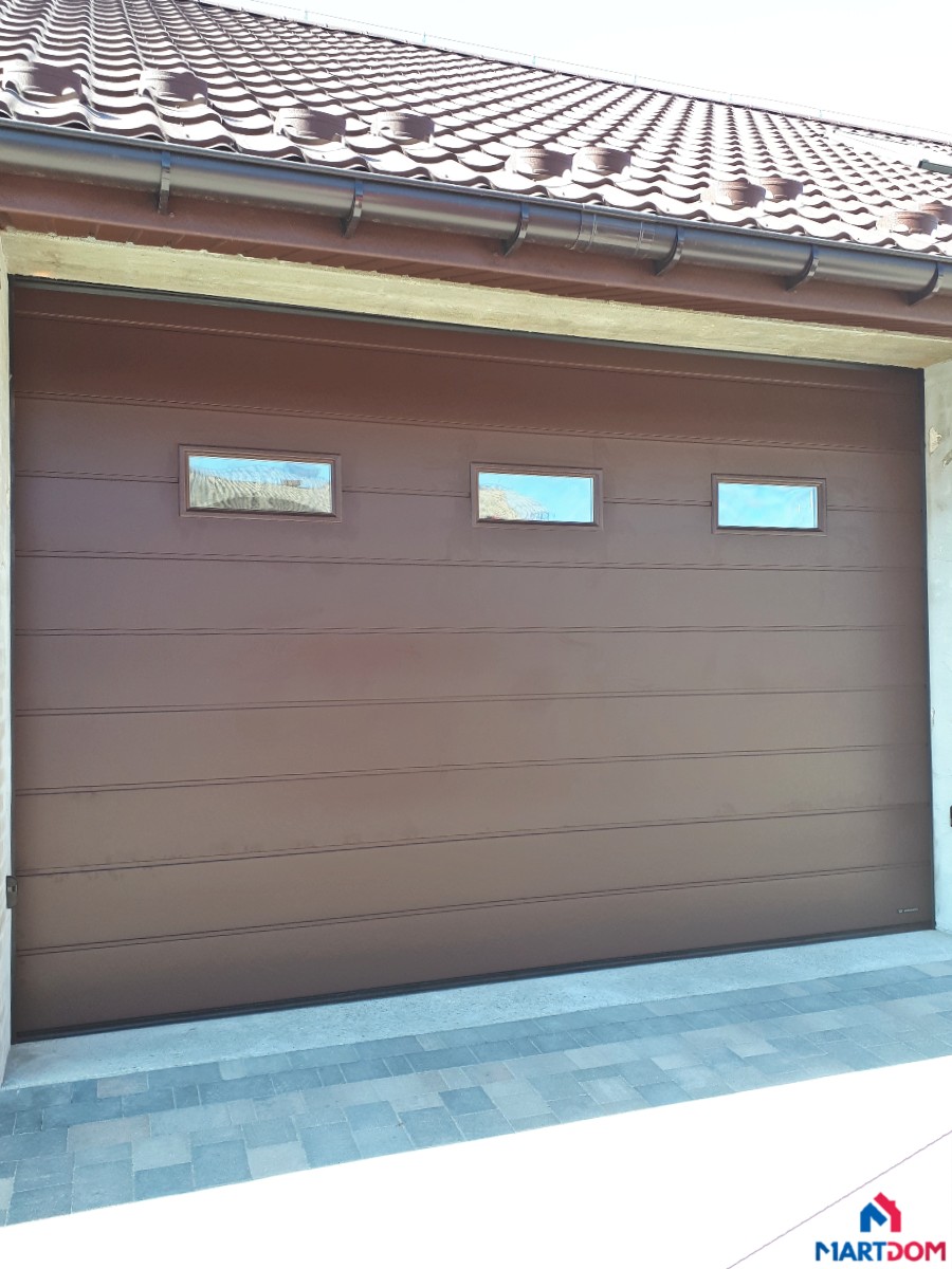 Produkt: Brama garażowa segmentowa UniPro Producent: Wiśniowski Kolor: RAL 8017 (brąz czekoladowy) Szczegóły: Brama z oknami typu A-1 (3 okna prostokątne) i panelami z przetłoczeniem wysokim (pojedynczym)