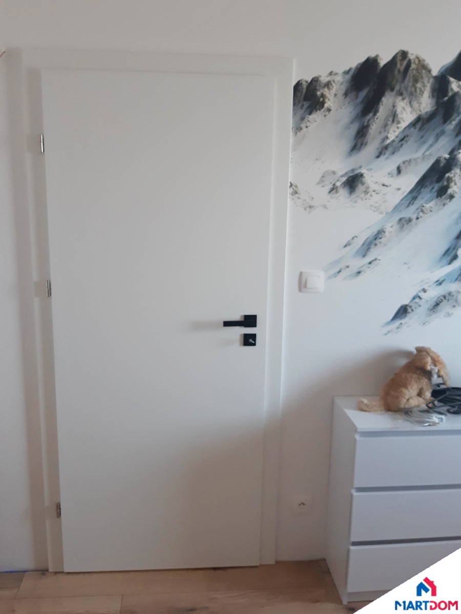 Białe drzwi wewnętrzne pokojowe lakierowane pełne gładkie tapeta góry jasny pokój jasna podłoga czarny akcent klamki klamka z szyldem na klucz martdom porta