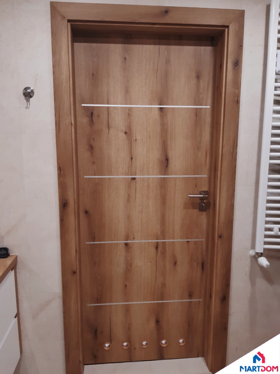 Drzwi DRE łazienkowe z tulejami w drewnianym odcieniu pełne bez szyb z intarsjami srebrnymi i klamką nikiel satyna montowane przez MartDom montaż drzwi Kraków w łazience drzwi 80