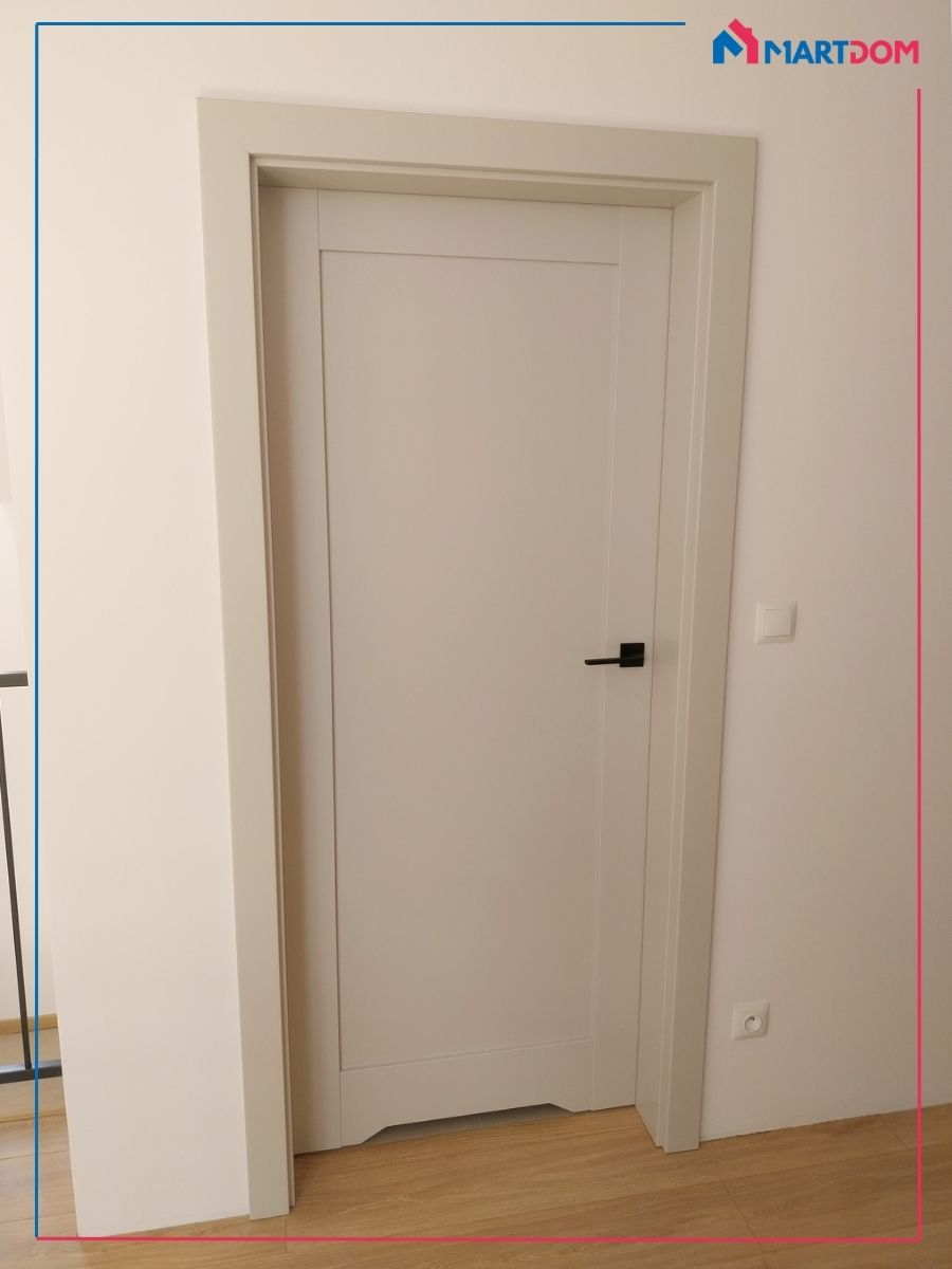 drzwi w kolorze kaszmir na korytarzu otwierane od środka z czarną klamką na białej ścianie i drewnianej podłodze połączenie kaszmiru bieli drewna