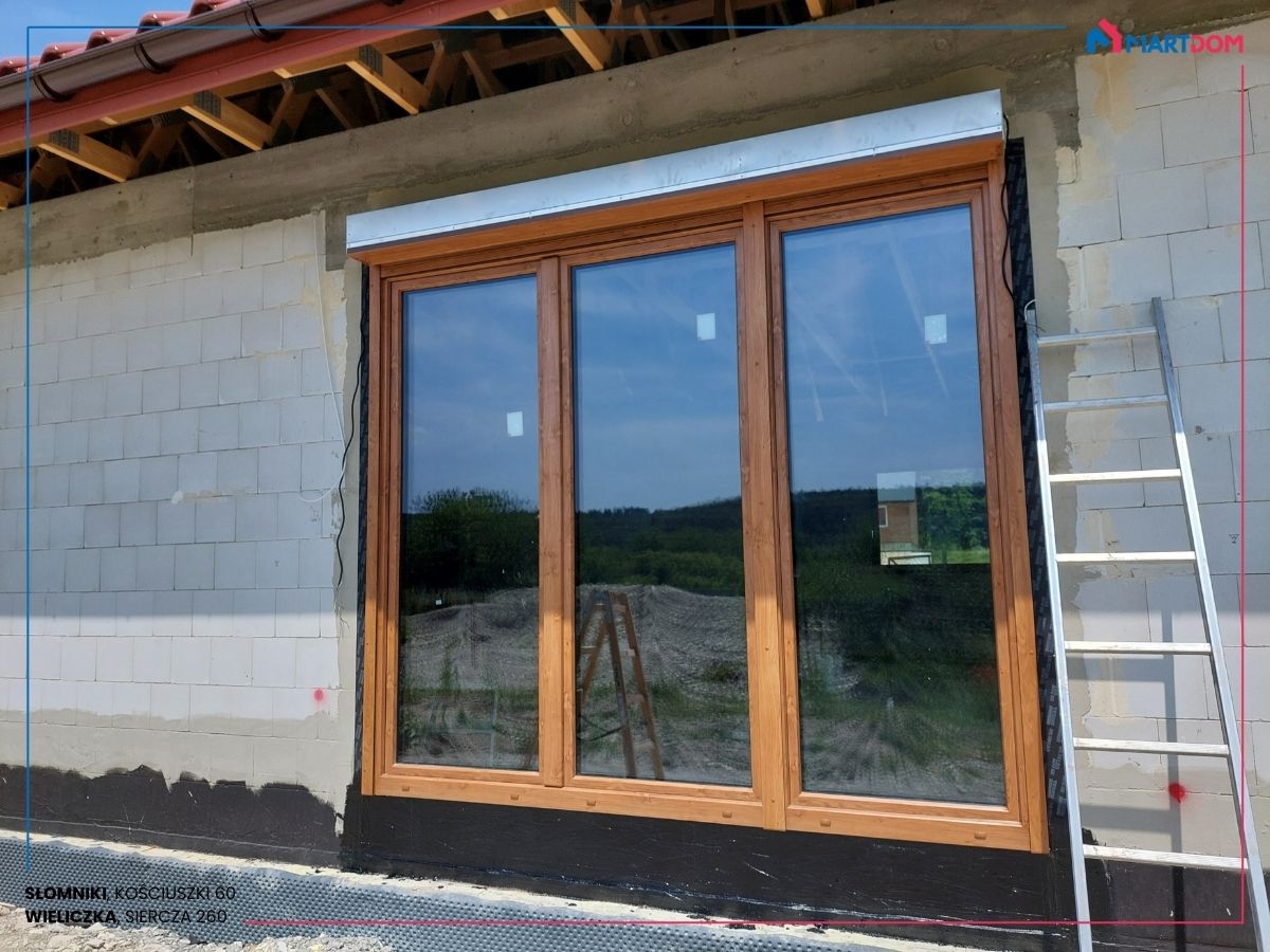 Balkon trzykwaterowy balkon z trzema skrzydłami w kolorze dąb khaki z roletą zewnętrzną w kolorze winchester montaż w domu jednorodzinnym nowe okna adams i rolety portos budowa domu w stanie surowym